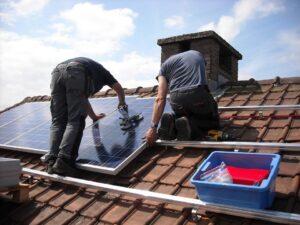 Männer verlegen Solarplatten auf Dach