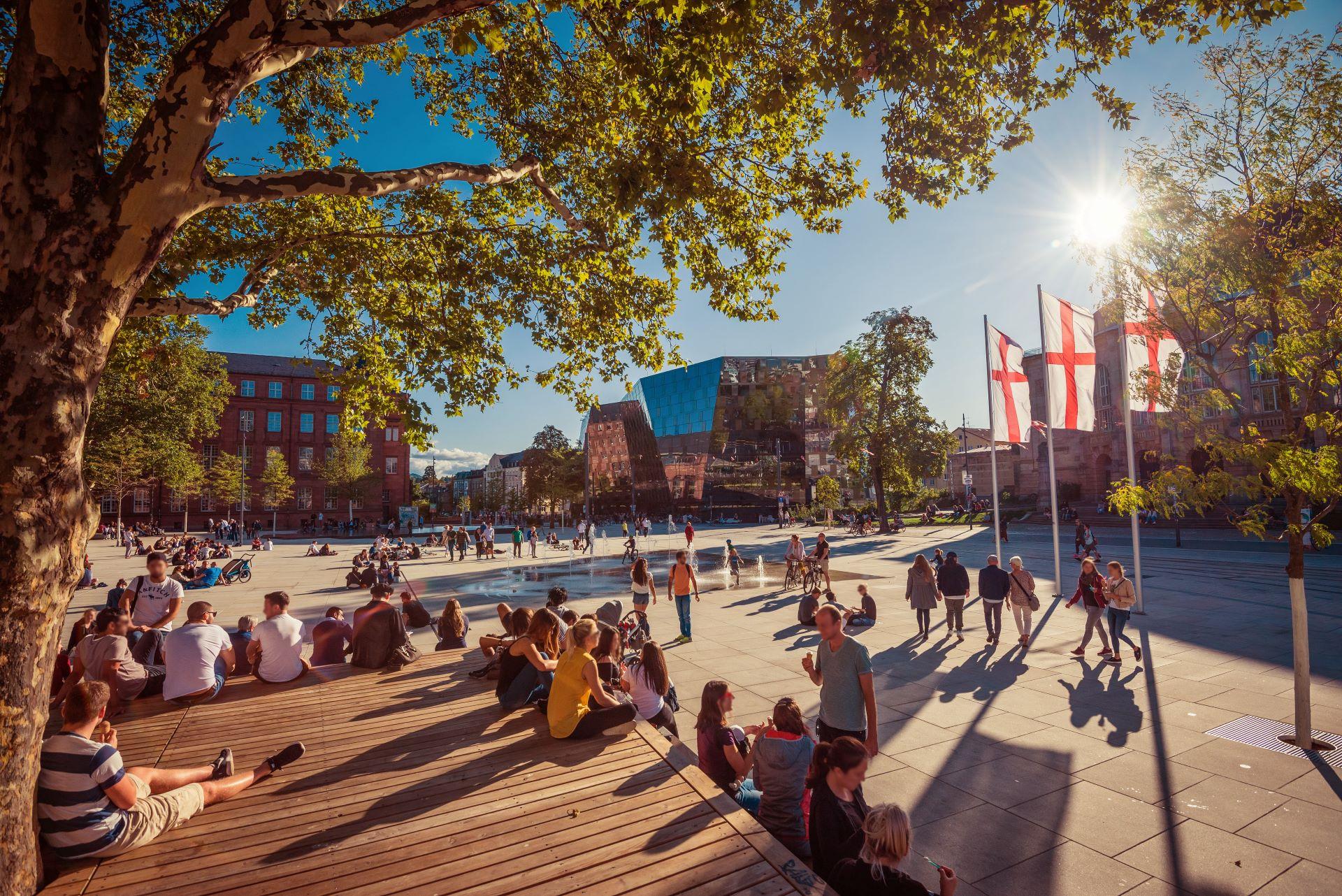 Sonniger Platz in Freiburg mit Menschen, Symbol für Lebensqualität.